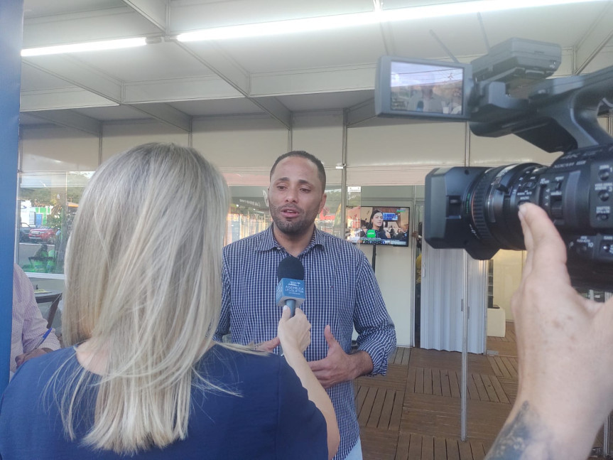 O deputado Do Carmo (União) sendo entrevista pela TV Assembleia em frente ao estande da Assembleia Itinerante.