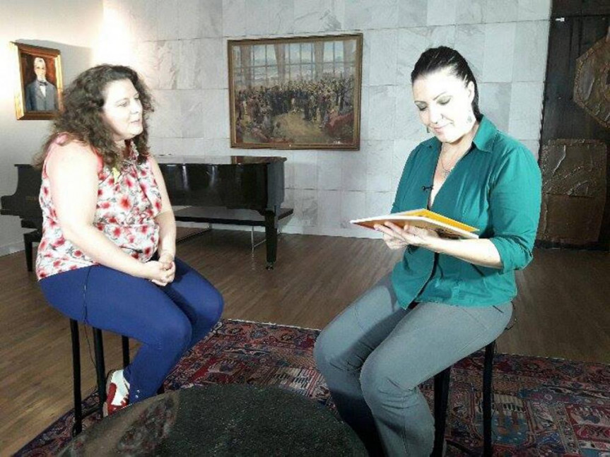 A repórter Simone Giacometti apreciando o livro da escritora Yvette Pais, durante entrevista do Programa " Autores Paranaenses".