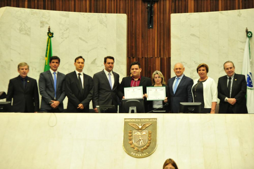 Um dos vencedores do Geração Atitude 2018, Luiz Augusto Rodrigues e sua professora Genice Bratti recebem a premiação do presidente Ademar Traiano (PSDB), ao lado do governador eleito Ratinho Junior (PSD) e deputados presentes.